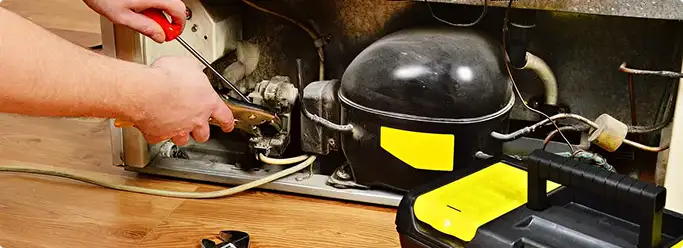 Refrigerator repair technician fixing the compressor and wiring in Groveland, IL