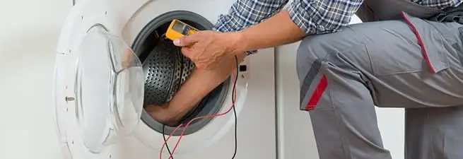 Dryer repair technician inspecting and repairing a clothes dryer in Peoria, IL