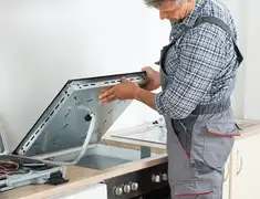 Appliance repair technician installing a built-in cooktop in Peoria, IL