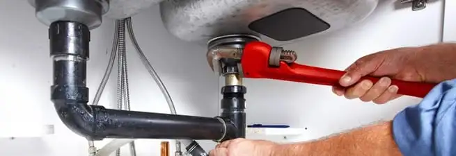 Garbage disposal repair technician tightening the sink drain and disposal connection in Peoria, IL