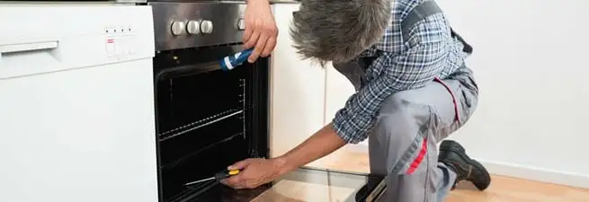 Oven repair technician inspecting and servicing an electric oven in Peoria, IL