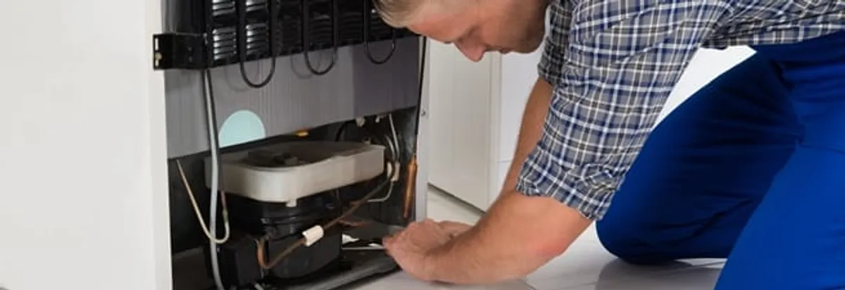 Refrigerator repair technician servicing the compressor and condenser area in Peoria, IL