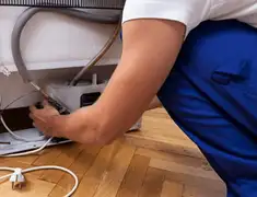 Appliance repair technician fixing refrigerator water line and connections in Peoria, IL