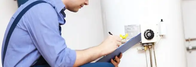 Water heater repair technician inspecting the unit and recording service notes in Peoria, IL