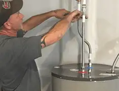 Water heater repair technician tightening supply line connections in Peoria, IL