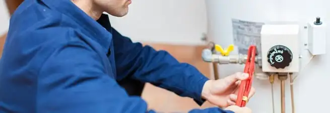 Water heater repair technician adjusting the temperature control and gas valve in Peoria, IL